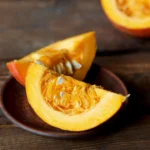 Calabaza cortada por la mitad sobre una tabla, lista para ser cocinada y utilizada en nuestros desayunos saludables de otoño.