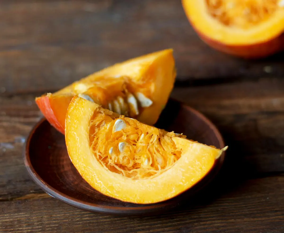 Calabaza cortada por la mitad sobre una tabla, lista para ser cocinada y utilizada en nuestros desayunos saludables de otoño.